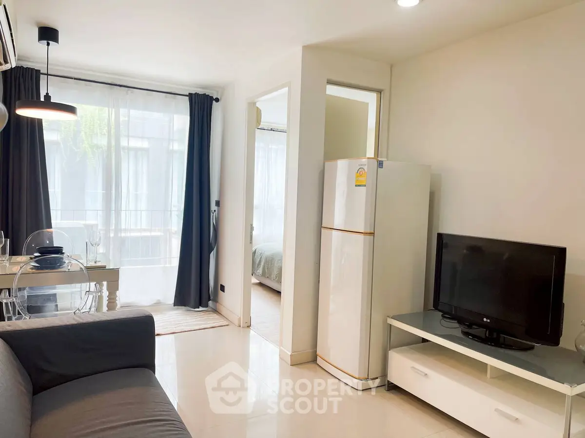 Modern living room with sleek furniture and natural light, featuring a cozy dining area and a glimpse of the bedroom.