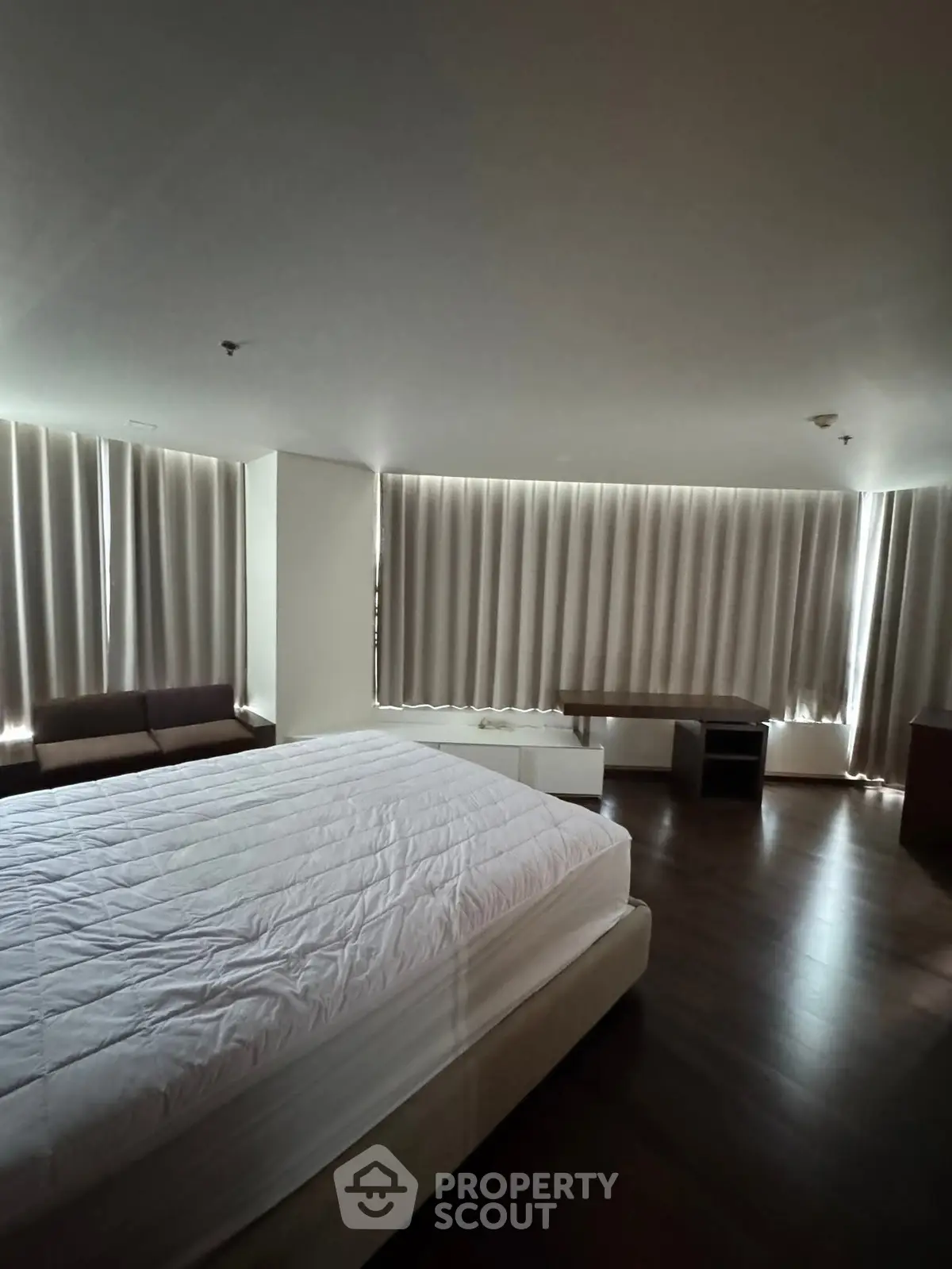 Spacious bedroom with modern furnishings and large windows for natural light.