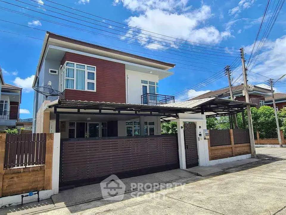 Modern two-story house with gated entrance and carport under clear blue sky.