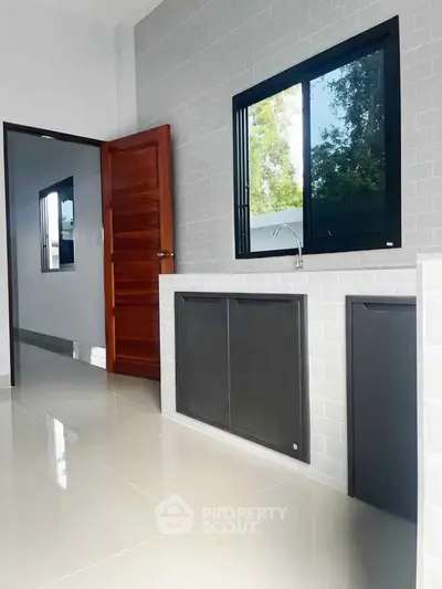 Modern kitchen with sleek cabinetry and large window for natural light.