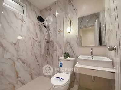Modern bathroom with marble tiles, sleek fixtures, and a large mirror, showcasing elegant design and functionality.