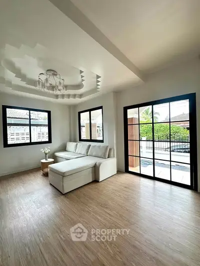 Spacious living room with modern decor and large windows overlooking a serene outdoor view.