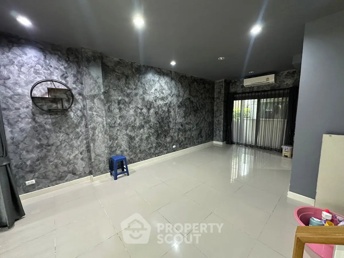 Spacious modern living room with stylish textured walls and large windows.