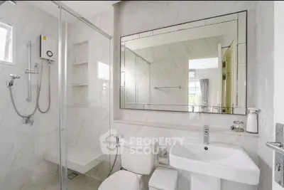 Modern bathroom with sleek fixtures and large mirror in a bright, elegant setting.
