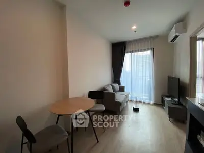 Modern living room with cozy sofa, dining table, and large window for natural light.