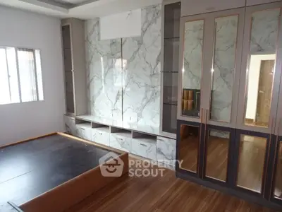 Spacious bedroom with elegant marble accent wall and wooden flooring