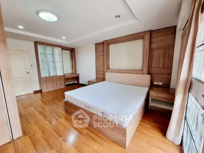 Spacious bedroom with wooden flooring and modern furnishings in a bright apartment.