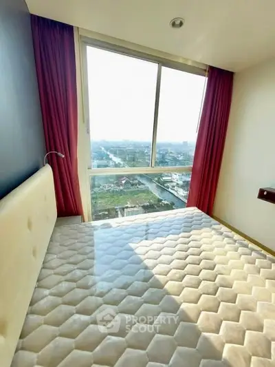 Bright bedroom with large window offering stunning city view and red curtains