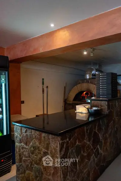 Charming rustic kitchen with stone counter and traditional pizza oven, perfect for culinary enthusiasts.