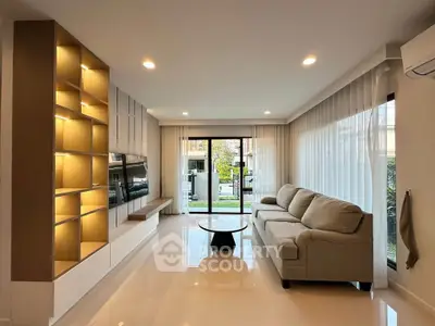 Modern living room with large windows and stylish shelving, offering a bright and inviting atmosphere.