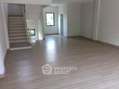 Spacious living room with gleaming hardwood floors, ample natural light, and a modern staircase leading to the upper level, perfect for elegant living.