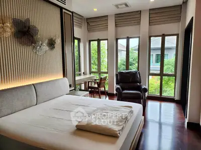 Spacious bedroom with large windows and garden view, featuring modern decor and comfortable furnishings.