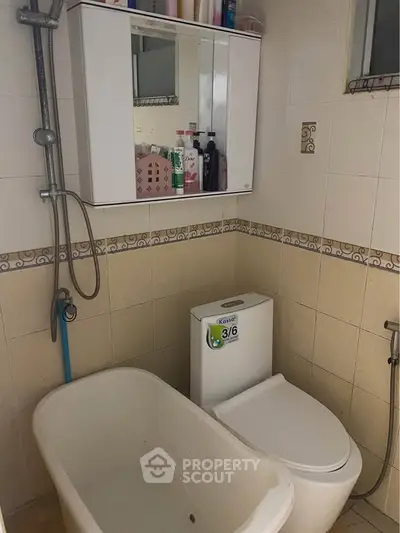 Compact bathroom with bathtub and wall-mounted storage cabinet.