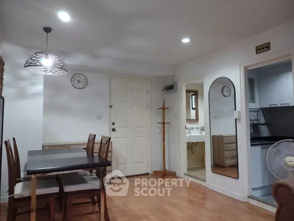 Charming dining area with modern lighting and wooden flooring in cozy apartment.