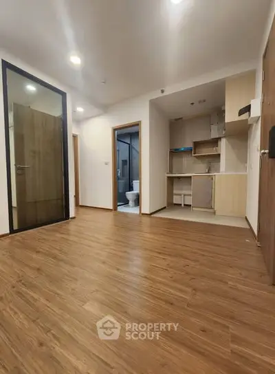 Modern open-plan apartment with wooden flooring and compact kitchen area.