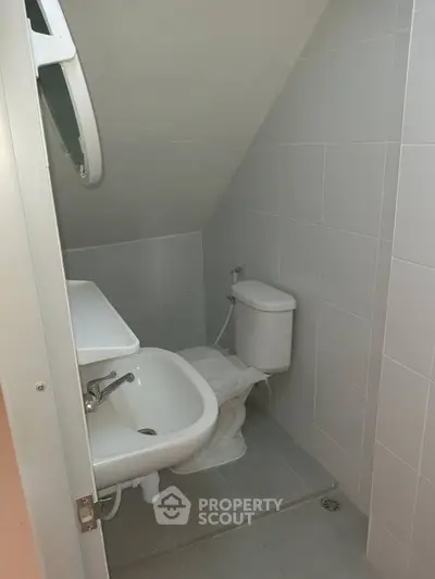 Compact bathroom with modern fixtures and sloped ceiling, ideal for small spaces.