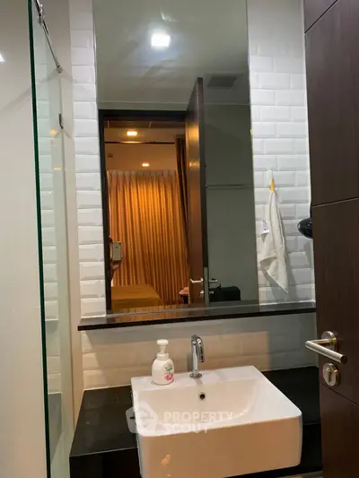 Modern bathroom with sleek sink and mirror reflecting a cozy bedroom view.