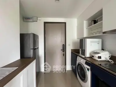 Modern kitchen with washing machine and sleek appliances in a compact layout.