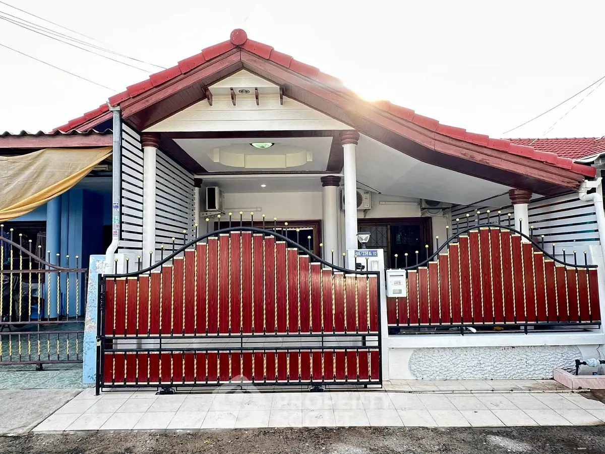 Charming single-story house with red roof and gated entrance, perfect for cozy living.