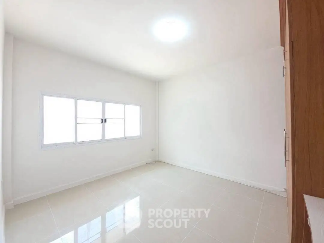 Spacious empty room with large window and glossy tiled floor, perfect for customization.