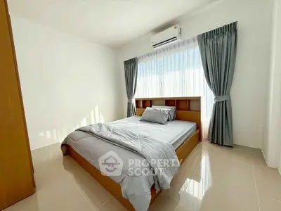 Bright and airy bedroom with modern furnishings and large window, perfect for relaxation.