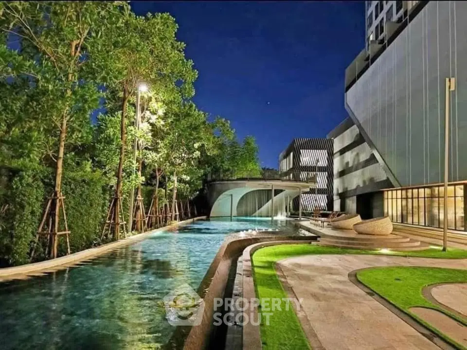 Luxurious modern apartment complex with stunning pool and lush greenery at night.