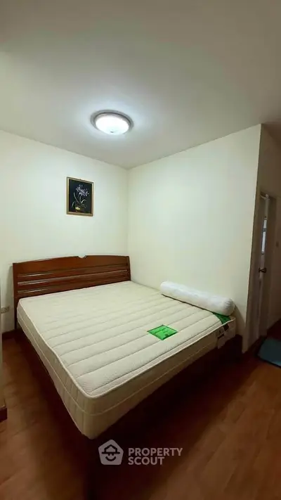 Spacious bedroom with wooden flooring and cozy lighting, featuring a comfortable bed and elegant wall art.