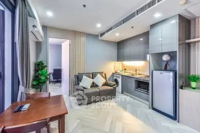 Modern living room with open kitchen, sleek cabinetry, and cozy seating area in a stylish apartment.