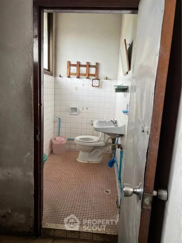 Cozy bathroom with tiled walls and floor, featuring a toilet and sink, ideal for compact living spaces.