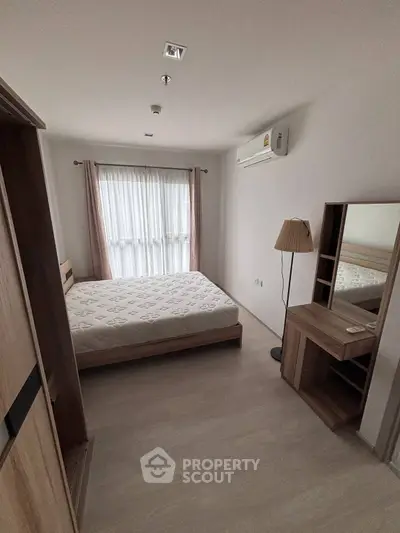 Cozy bedroom with natural light, featuring a bed, wardrobe, and dressing table, perfect for relaxation.