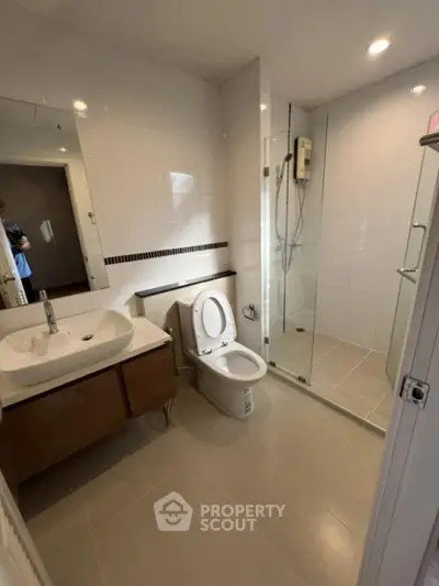 Modern bathroom with glass shower and sleek vanity in contemporary apartment.