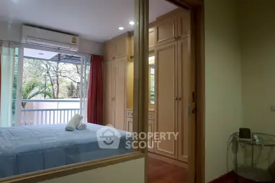Cozy bedroom with balcony view, featuring built-in wardrobes and air conditioning.