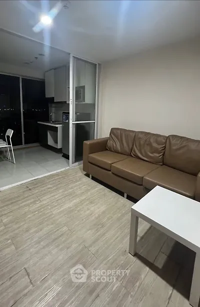Modern living room with brown leather sofa and open kitchen layout, featuring sleek design and city view.