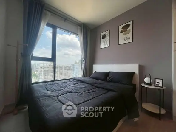 Modern bedroom with large window offering city view, stylish decor, and cozy ambiance.