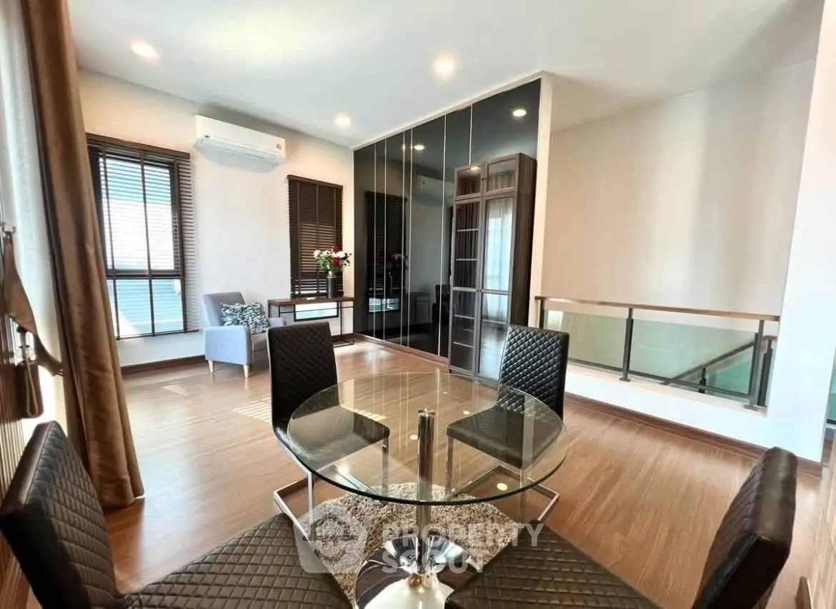 Modern dining area with glass table and stylish chairs in a bright, open-plan living space.
