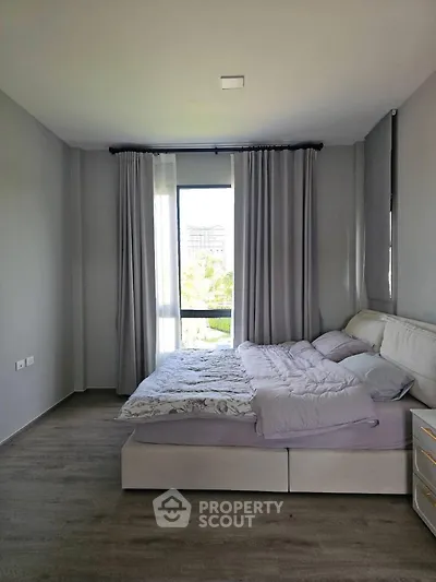Spacious bedroom with modern decor and large window offering natural light.