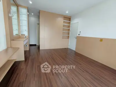 Spacious modern living room with wooden flooring and built-in shelves, perfect for stylish urban living.