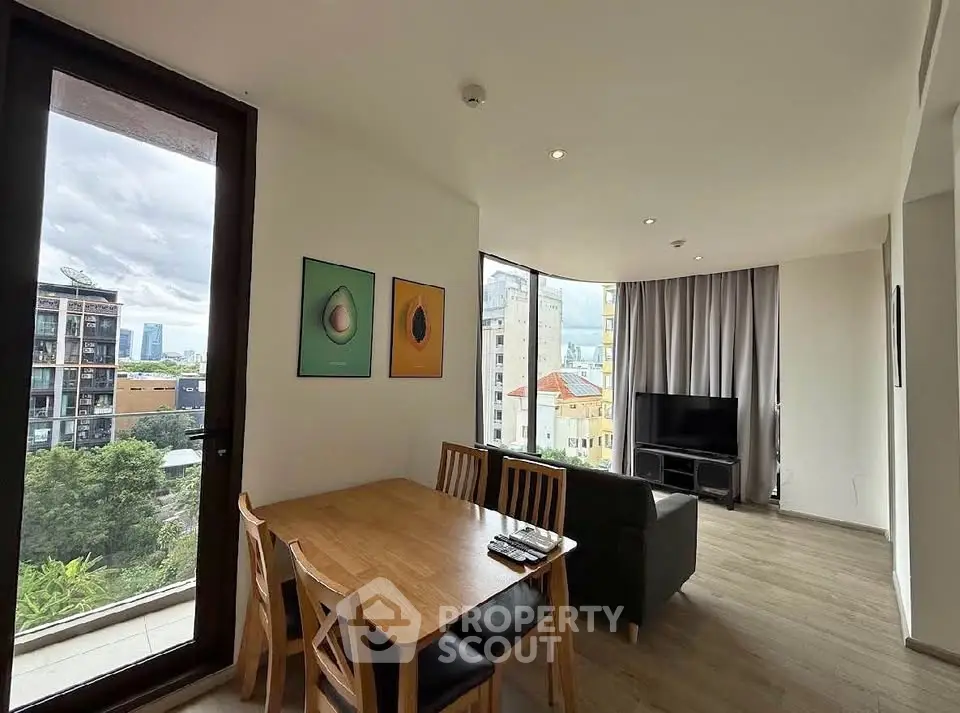 Modern living room with large windows and city view, featuring dining area and cozy seating.