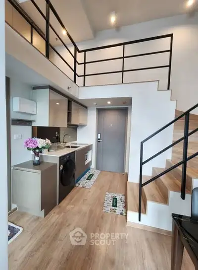 Modern loft apartment with stylish kitchen and staircase, featuring open layout and contemporary design.