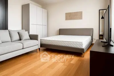 Modern bedroom with sleek furniture and hardwood floors, featuring a cozy sofa and stylish decor.