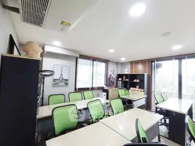 Modern study room with green chairs and ample natural light, perfect for collaborative work.