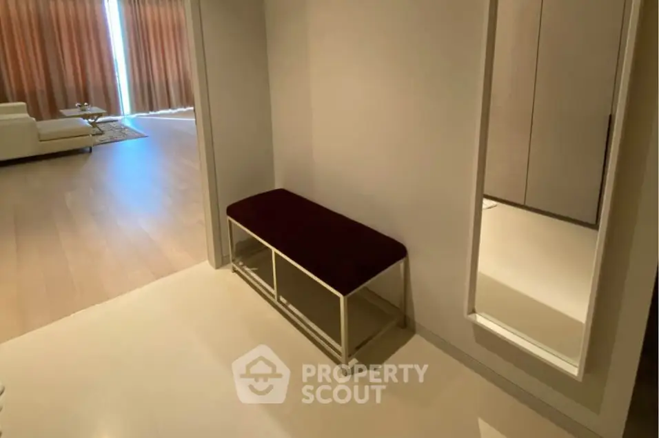 Modern interior hallway with bench and mirror leading to a stylish living room.