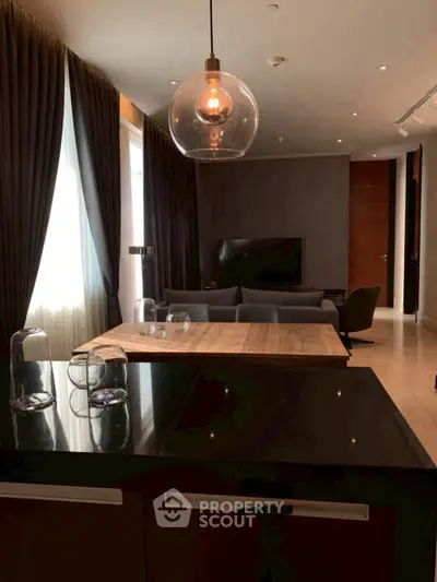 Modern living room with elegant lighting and stylish furniture, featuring a sleek open kitchen design.