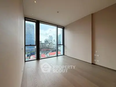 Spacious empty room with floor-to-ceiling windows offering stunning city views in a modern high-rise building.