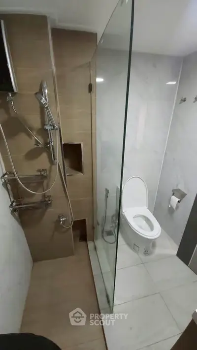 Modern bathroom with glass shower and sleek fixtures in contemporary apartment.