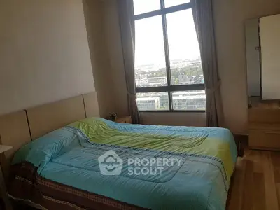 Bright bedroom with large window offering stunning city view, featuring a cozy bed and wooden flooring.