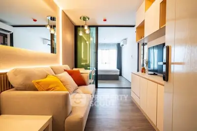 Modern living room with cozy sofa and stylish decor leading to a bright bedroom.