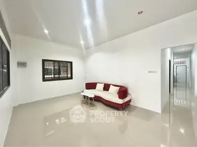Spacious living room with modern red and white sofa and glossy tiled floors.