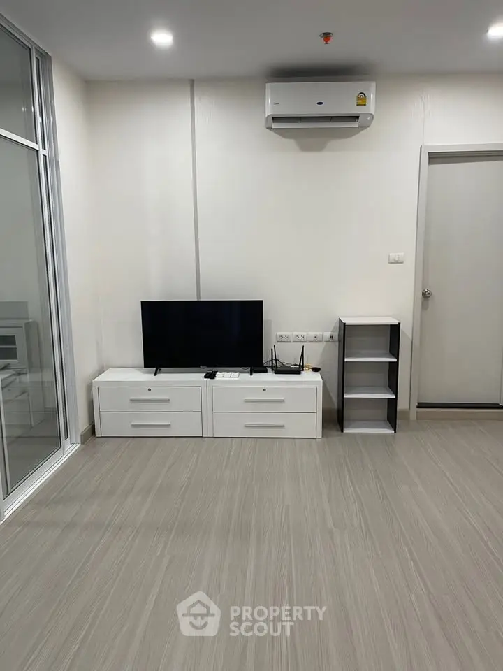 Modern living room with sleek flooring and air conditioning unit, featuring a minimalist TV setup.