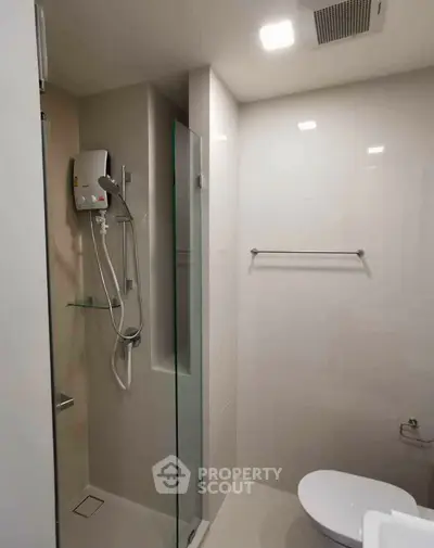 Modern bathroom with sleek shower and toilet in a minimalist design.
